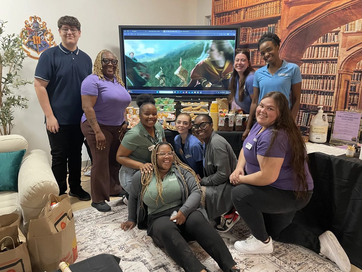 Group of colleagues smiling and posing in front of a television, with snacks and McDonald’s food.